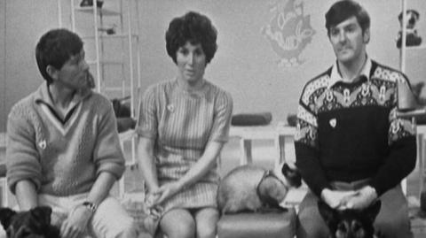 John Noakes, Valerie Singleton and Peter Perves sit on a sofa with a cat and a dog