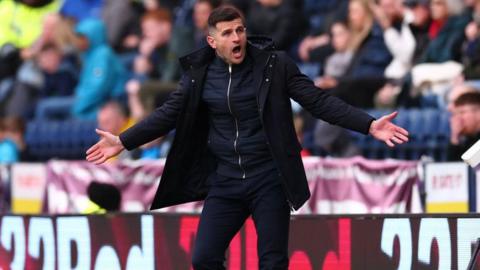 Portsmouth boss John Mousinho, arms outstretched, during his side's defeat away at Preston North End