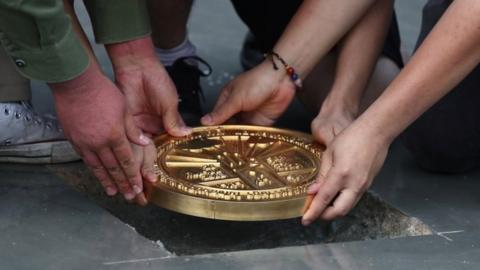 Student leaders install a plaque declaring: "This country belongs to the people"