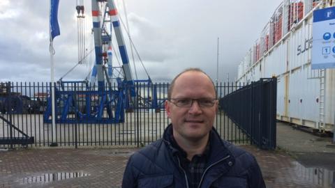 Peter Westdijk in front of cranes at the port of Rotterdam