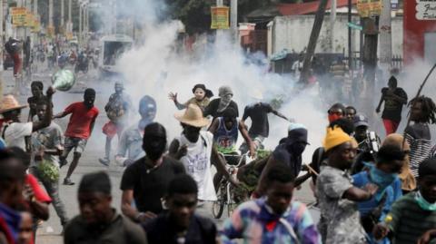 People run while police fire tear gas during a protest demanding the resignation of Haiti's Prime Minister Ariel Henry after weeks of shortages, in Port-au-Prince, Haiti October 10, 2022. REUTERS/Ralph Tedy Erol