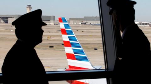 Pilots talk as they look at the tail of an American Airlines aircraft at Dallas-Ft Worth International Airport February 14, 2013