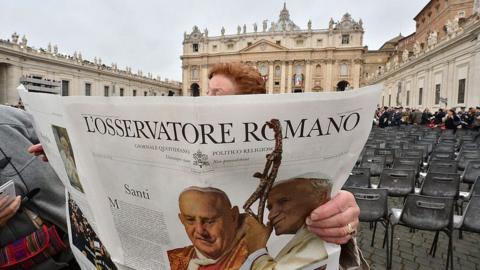 A woman reads L'Osservatore Romano newspaper before the canonisation mass of Popes John XXIII and John Paul II at St Peter's, April 2014