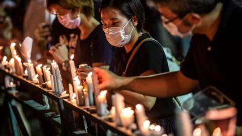 A woman (C) places a candle on a railing during a candlelit remembrance in Victoria Park in Hong Kong on June 4, 2020