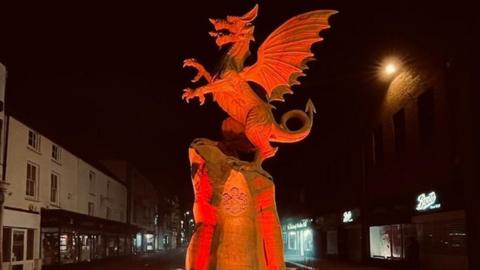 a sculpture of a dragon illuminated orange
