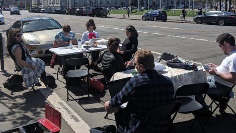 People sit at a desk in a parking space