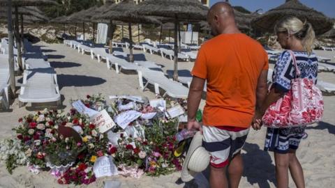 Tourists look at flowers on Tunisia beach