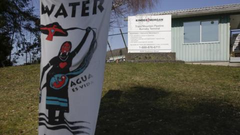 A sign protesting the Trans Mountain pipeline project is pictured in front of its terminal in British Columbia