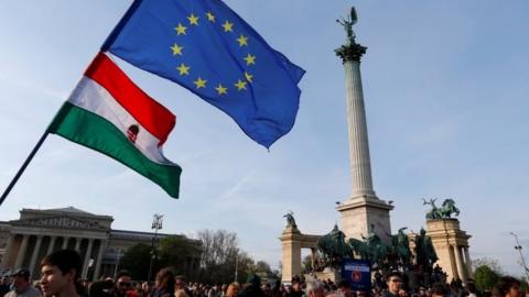 People wave Hungarian and European Union flags as they protest in Heroes square against a new law that would undermine Central European University in Budapest, Hungary on 12 April 2017