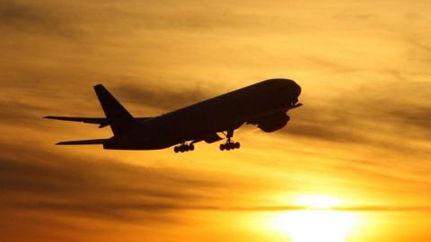 plane flying against sunset backdrop