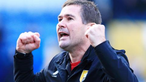 Mansfield boss Nigel Clough with his two fists up as he celebrates a win