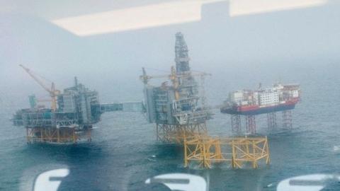 People sitting in a helicopter are reflected in its window as they wait to land at the Johan Sverdrup oil field in the North Sea outside of Norway on October 9 2018. - The power-from-shore solution will make Johan Sverdrup one of the most carbon-efficient fields worldwide.