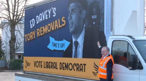 Ed Davey with 'Tory removals' poster