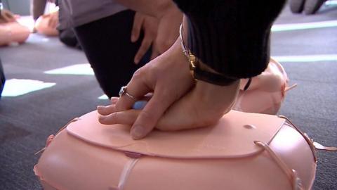 Hands pressing down on a CPR dummy