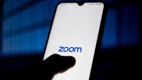 Zoom Meetings logo is seen displayed on a smartphone