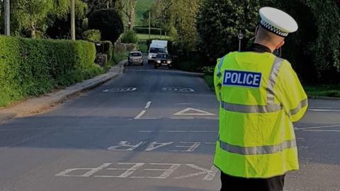 A police officer standing in the road with a speed camera