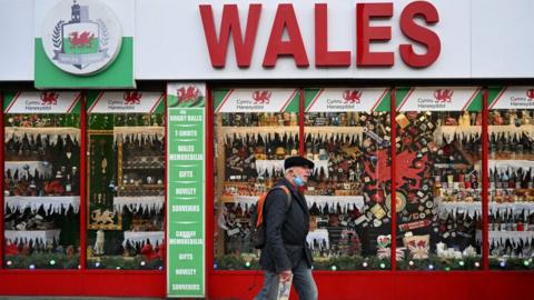 A man wears a face mask as he walks past a Wales souvenir store in Cardiff
