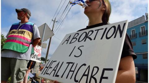 An abortion rights activist holds a placard saying "abortion is healthcare" outside Mississippi's only abortion clinic