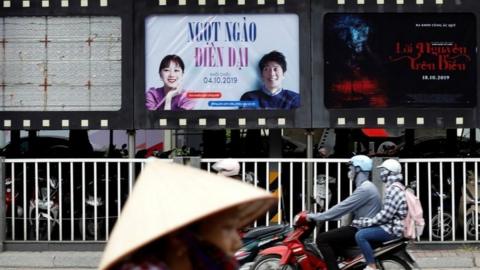 Bikers go past an empty space where a promotional poster for "Abominable" stood before being taken down at a cinema in Hanoi