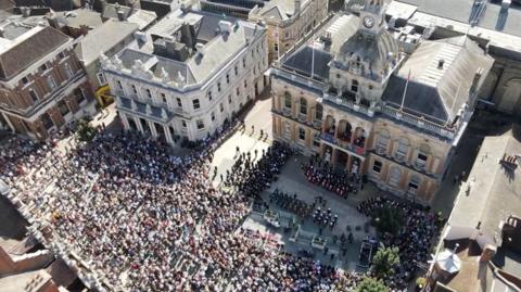 Hundreds of people gather at a town hall to hear the proclamation of accession of King Charles III.