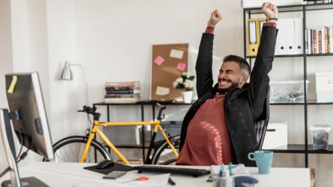 A man stretches behind a desk