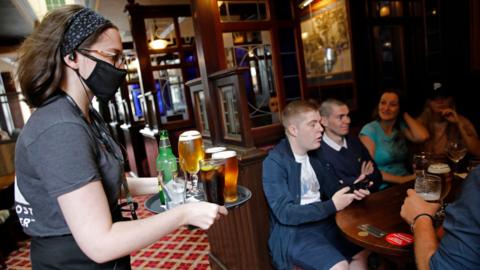 A bar worker serves customers at the Goldengrove pub in Stratford, east London