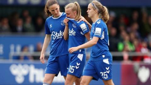 Aggie Beever-Jones of Everton, in tears, surrounded by two teammates as she walks off the pitch