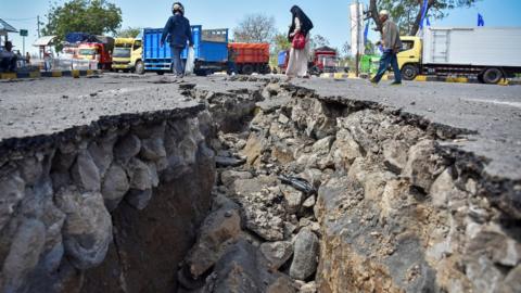 People walk near a road damaged by a large earthquake at Kayangan Port in Lombok, Indonesia.