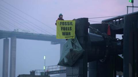 Activist having scaled berthing station with banner