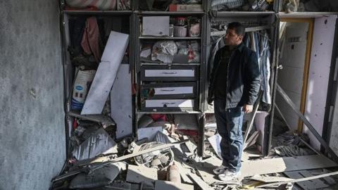 A man inspects a damaged house after several rockets land at Khair Khana in Kabul