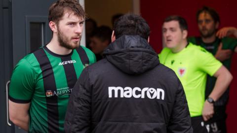 Match officials and Aberystwyth players wait for news at the USW Sport Park in Treforst