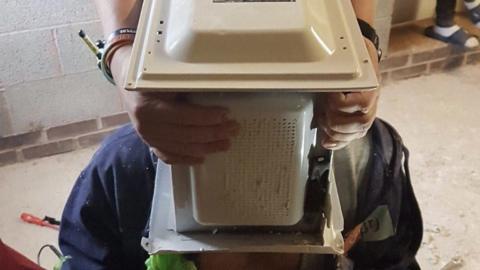 Jay Swingler with microwave on his head