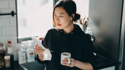 Woman looking at energy bill while having a cup of tea