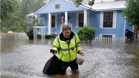 Flood victim carries food salvaged from his home - 29 August