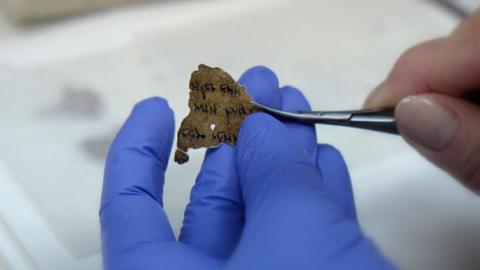 A worker of the Israeli Antiquity Authority sews fragments of the Dead Sea scrolls which includes biblical verses in a preservation laboratory of the Israel Museum in Jerusalem.