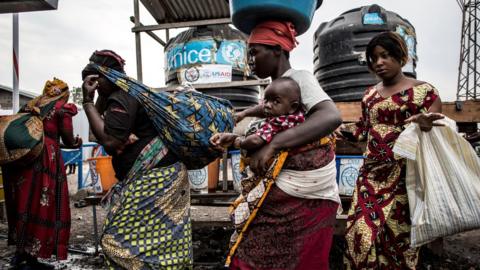 Women wash their hands at an Ebola screening station as they enter DR Congo from Rwanda