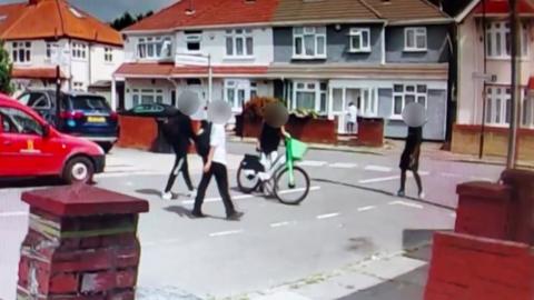 Image showing four teenagers parking a Lime Bike at the junction of a road in Hounslow.