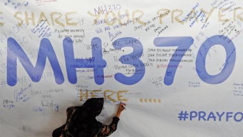 Woman writes messages on an MH370 tribute in Kuala Lumpur. File photo