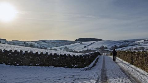 A cyclist on the snow at Blackmoss Reservoir in Barley, Pendle, Lancashire