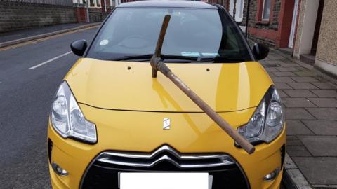 Damaged car with pickaxe in its bonnet