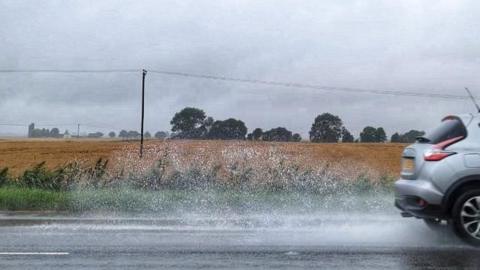 A car driving through the rain at Ramsey St Mary's, Cambridgeshire