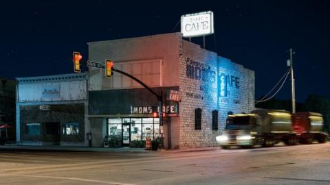 A night view of a closed cafe with a lorry passing