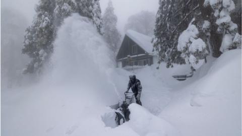 A Running Springs, California resident clears snow outside his home