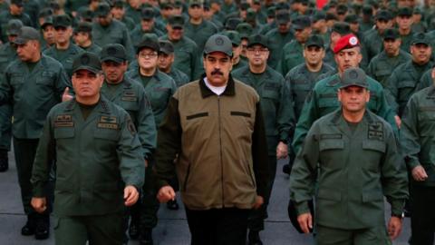 This handout picture released by Miraflores Palace press office shows Venezuela's President Nicolas Maduro waving military troops accompanied by Defense Minister Vladimir Padrino (L) at the "Fuerte Tiuna" in Caracas, Venezuela on May 2, 2019