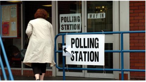 Stock image of woman walking in to polling station