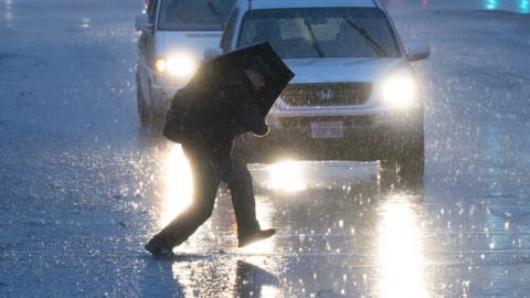 A pedestrian walks on the street against heavy rain as a bomb cyclone hits California