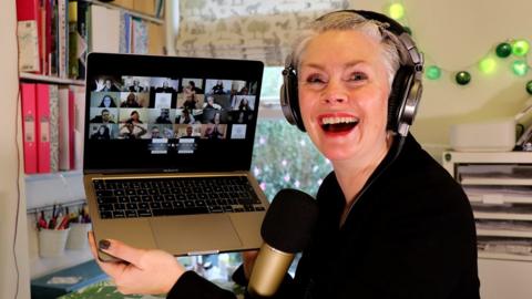 Kari Olsen-Porthouse from ICU Liberty Singers smiles as she holds her laptop during a virtual choir meeting