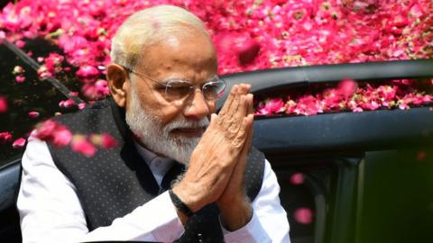 Indian Prime Minister Narendra Modi greets supporters as he arrives to file his election nomination papers in Varanasi.