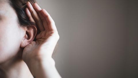 Woman with her hand cupped to her ear