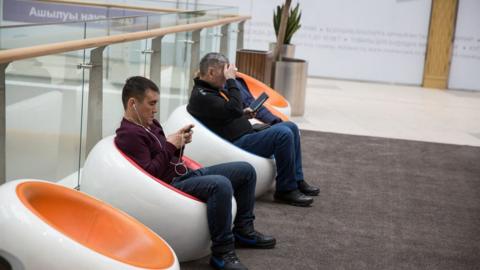 Men use their phones in a shopping centre in Astana, Kazakhstan
